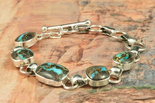 5 Beautiful Genuine Sunnyside Turquoise Stones set in Sterling Silver Bracelet. The matrix on this rare stone is outstanding. The Sunnyside mine is located in northern Nevada near the town of Tuscarora in the Tuscarora mountain range. The mine is no longer in operation as it has become part of a gold mining operation and a privately owned ranch. The Sunnyside mine was mined mostly in the 70's. You won't find much of this great turquoise around anymore except for old stashes. Created by Navajo Artist Tony Garcia. Signed by the artist.